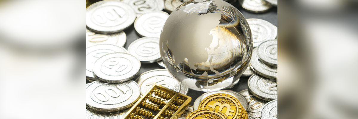 Globo transparente sobre monedas y símbolos financieros que representa economía global, finanzas y criptomonedas.