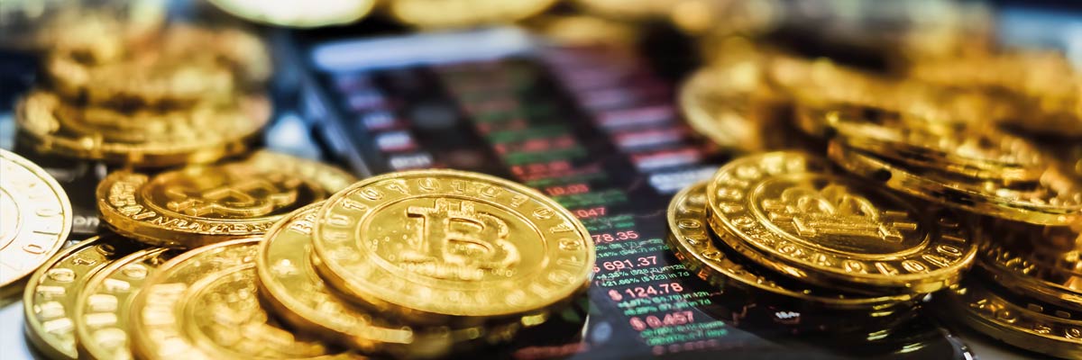 Monedas de bitcoin apiladas sobre una pantalla que muestra gráficos de cotizaciones