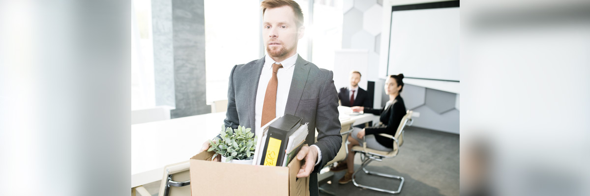 Empleado sale de la oficina con caja de pertenencias tras un despido; imagen sobre despido y transición laboral.