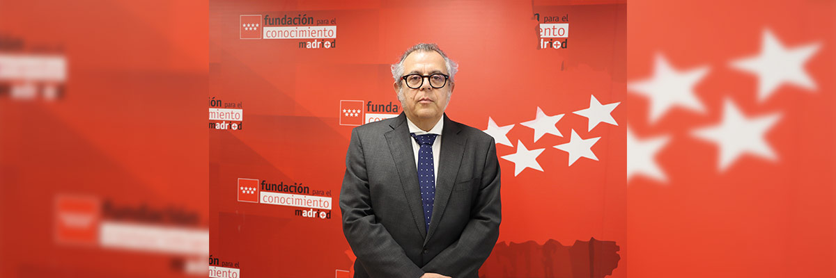 Manuel Lucena Giraldo frente a un fondo rojo con logotipos y estrellas, destacando la identidad visual de la “Fundación Conocimiento