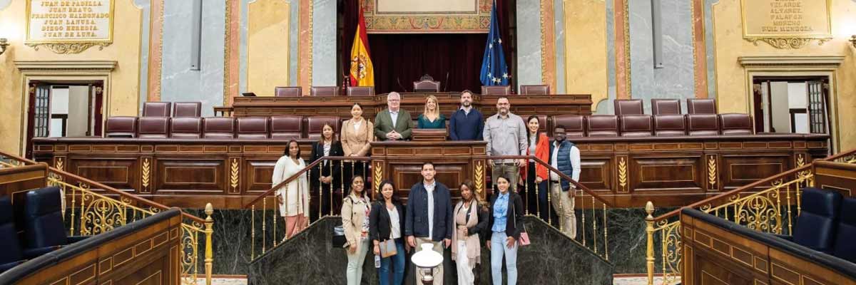 Grupo de visitantes en el hemiciclo del Congreso de los Diputados, foto institucional durante visita guiada.