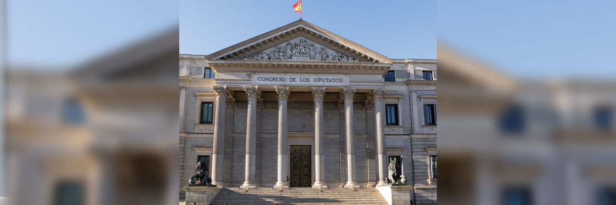 Fachada neoclásica del Congreso de los Diputados en Madrid, con columnas y escalinata bajo cielo azul