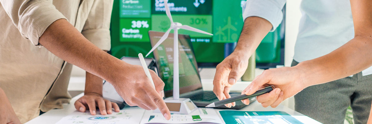 Tres personas trabajando en una presentación o análisis empresarial de datoso que representan energías verdes