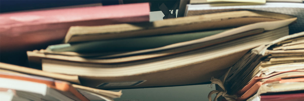 Pila desordenada de carpetas y expedientes apilados sobre un escritorio, simbolizando burocracia.