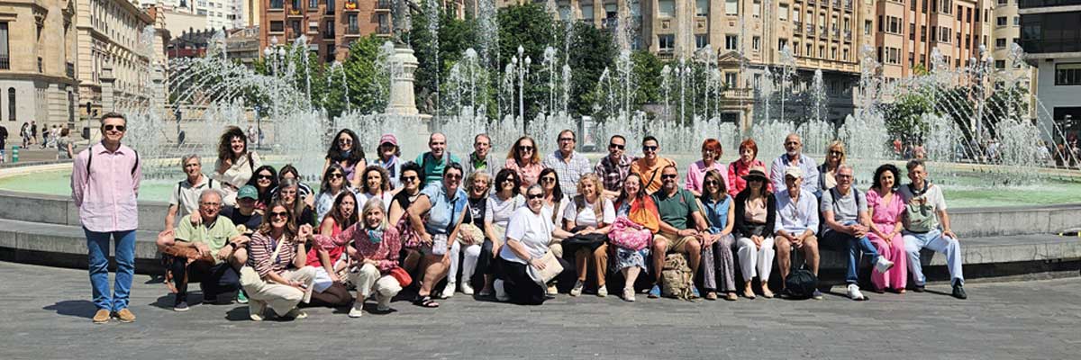 rupo de personas reunidas frente a fuente en plaza urbana con edificios