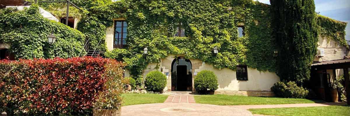 Fachada rústica cubierta de hiedra con jardín cuidado y sendero que conduce a la entrada principal.
