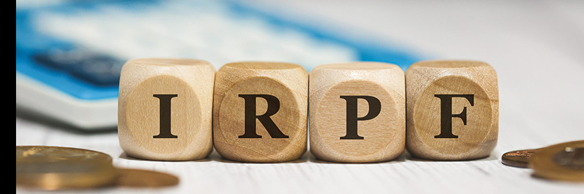 Bloques con letras "IRPF" junto a monedas y calculadora, símbolo de la declaración y gestión del impuesto sobre la renta.