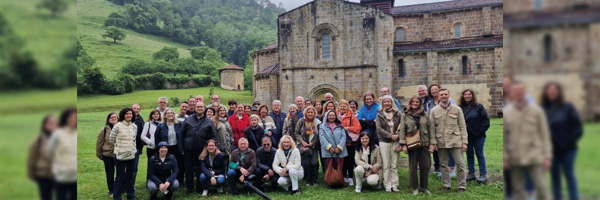 Grupo de personas posando frente a un edificio de piedra antiguo con colinas verdes al fondo