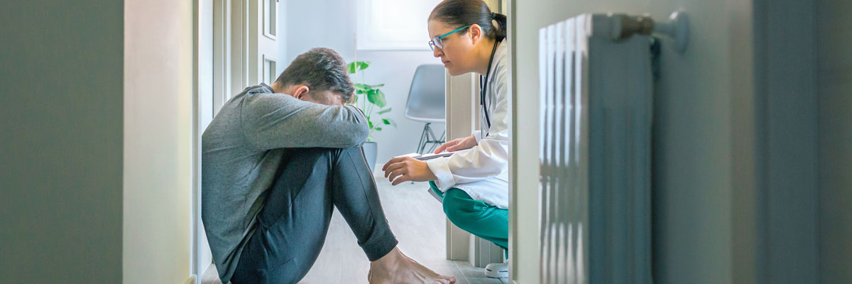 Paciente descalzo en pasillo hospitalario recibe apoyo emocional de médico con bata blanca
