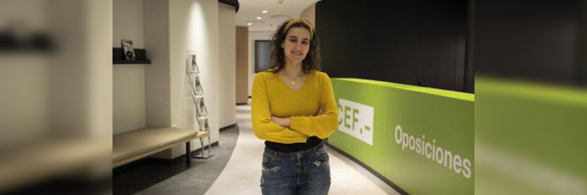 Mujer joven con suéter amarillo y vaqueros sonriendo en una sede del CEF.