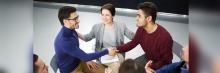 Personas sonrientes en círculo; dos hombres se estrechan la mano durante una sesión de networking y diálogo.