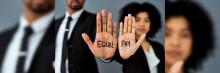La imagen muestra dos individuos con “EQUAL PAY” en sus palmas, simbolizando la lucha por la igualdad salarial.