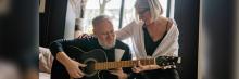 Persona mayor toca la guitarra guiada por terapeuta; música y mindfulness para prevenir la soledad.