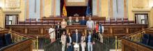 Grupo de visitantes en el hemiciclo del Congreso de los Diputados, foto institucional durante visita guiada.