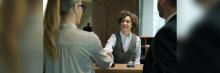 Recepcionista saluda a huéspedes en el mostrador durante el check-in; atención al cliente y gestión hotelera.