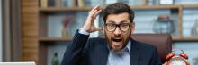 Hombre de oficina con gafas gritando mientras sostiene un reloj despertador rojo en actitud de urgencia.