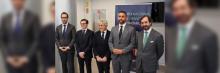 Grupo de cinco hombres de traje alineados frente a pancarta del I Torneo Nacional de Debate Económico en sala de conferencias