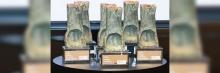 Varias estatuillas del Premio Estudios Financieros 2024 expuestas sobre una mesa redonda con base oscura