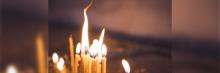 Primer plano de varias velas encendidas agrupadas, con la llama titilando sobre un fondo tenue