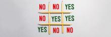 Texto “NO NO YES / NO YES YES / YES NO NO” formado con lápices dispuestos en un juego de tres en raya.